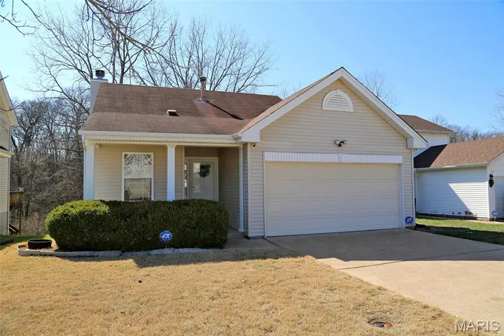 Ranch-style house featuring driveway, an attached garage, a front lawn, and a chimney