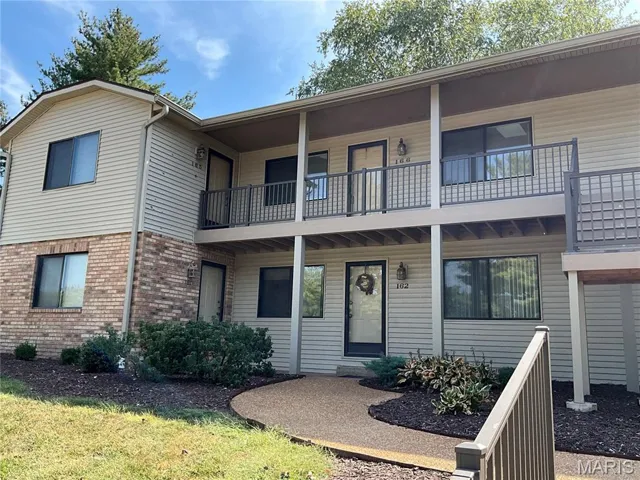 View of front of property with brick siding and a balcony