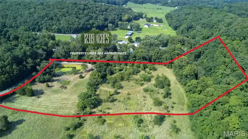 Aerial view of sparsely populated area with a forest and property parcel outlined