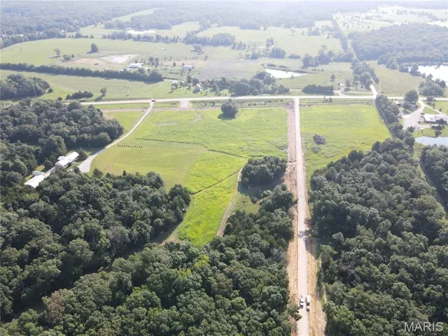 Aerial view of sparsely populated area with a forest and property parcel outlined