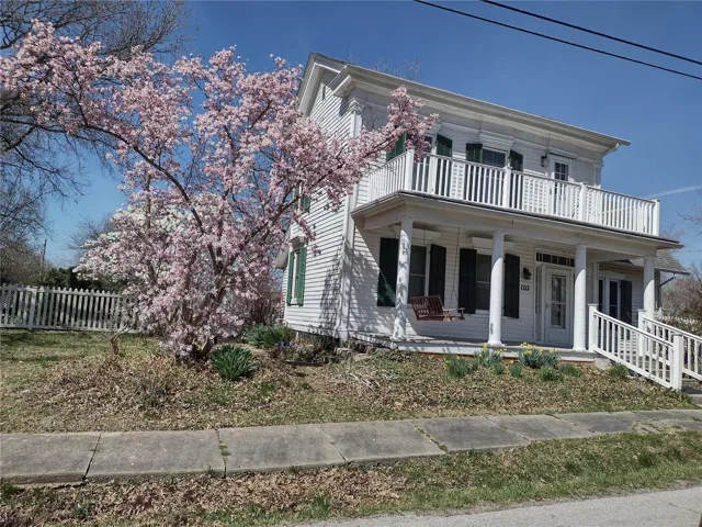 View of front of house featuring a balcony, fence, and a porch