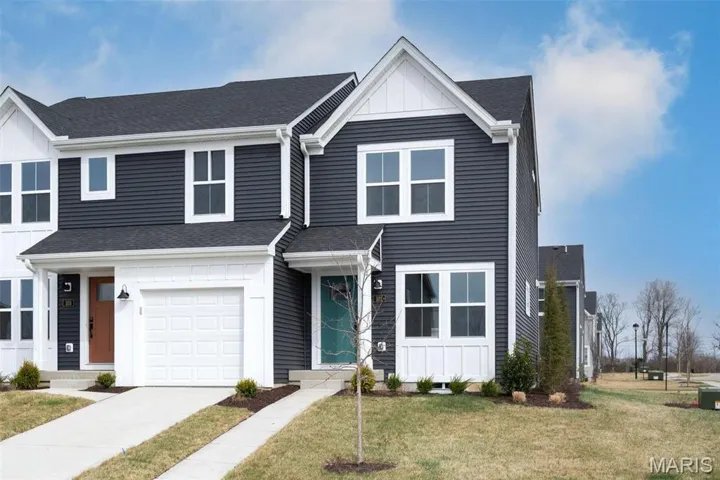 View of front facade with a front lawn, an attached garage, board and batten siding, and concrete driveway