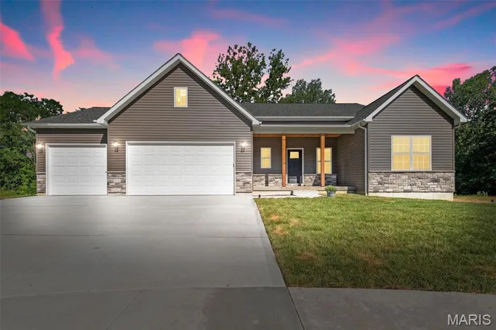 View of front of property featuring a garage, a lawn, and a porch