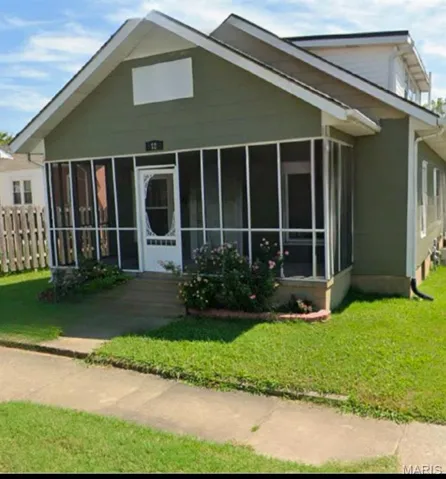 View of front of house featuring a sunroom, a front lawn, and fence