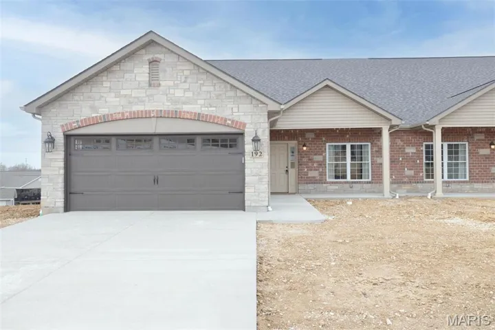 View of front facade with an attached garage, stone siding, driveway, and a shingled roof