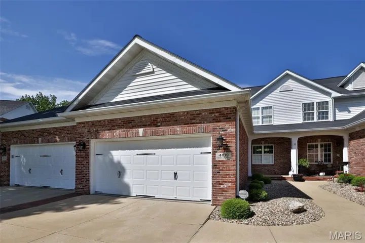 View of front of home with brick siding, driveway, and a garage