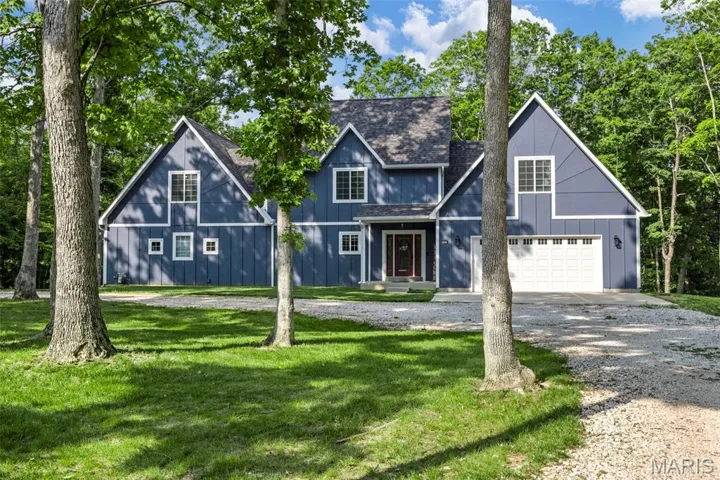View of front facade featuring driveway, a front yard, a shingled roof, and board and batten siding