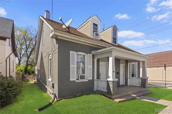 View of front of home with covered porch, a front yard, and brick siding