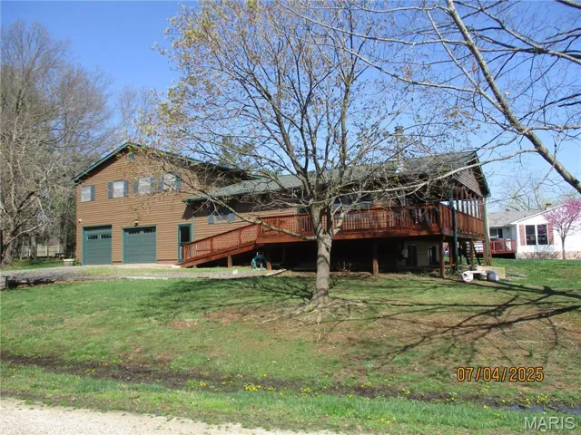 View of front of home with a garage, a front yard, and a deck
