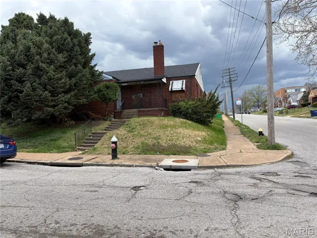 View of front of property featuring brick siding and a chimney