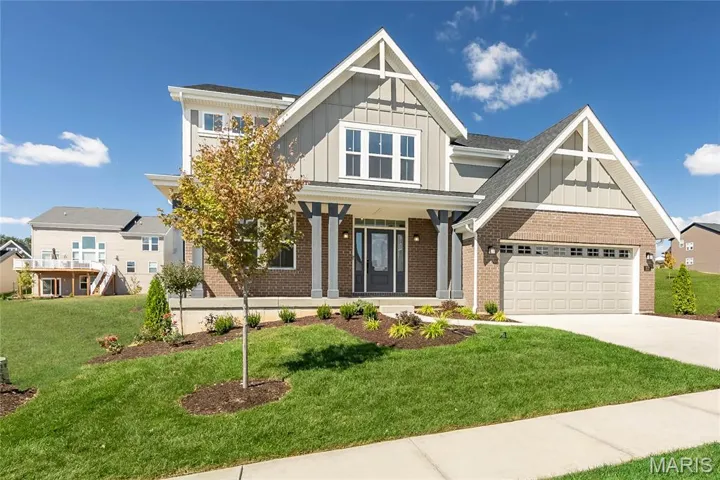 Craftsman-style house with board and batten siding, brick siding, a porch, concrete driveway, and a garage