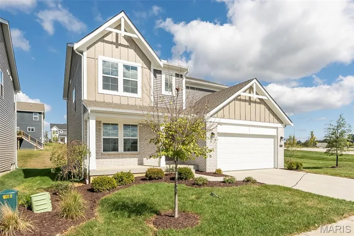 Craftsman house with board and batten siding, brick siding, a front lawn, concrete driveway, and a garage