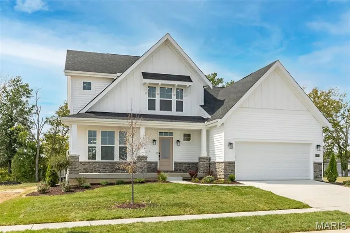 Modern farmhouse featuring board and batten siding, a shingled roof, covered porch, and a front yard