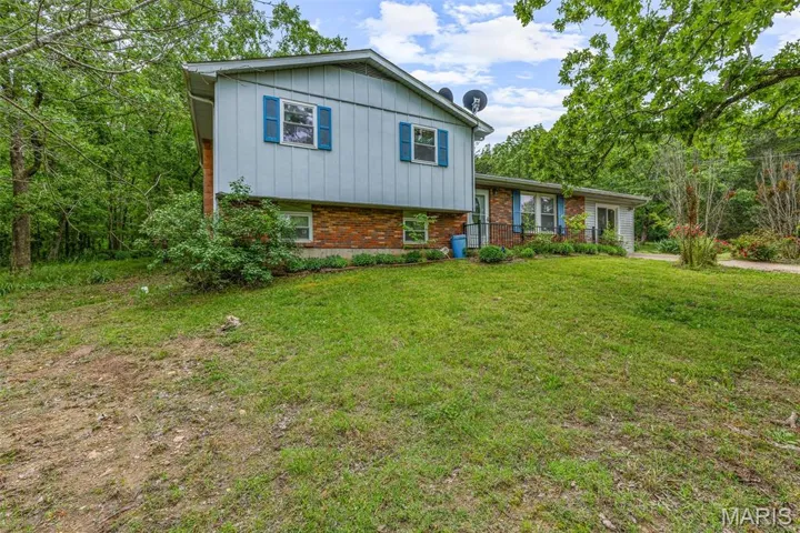 Split level home with brick siding, a front yard, and board and batten siding
