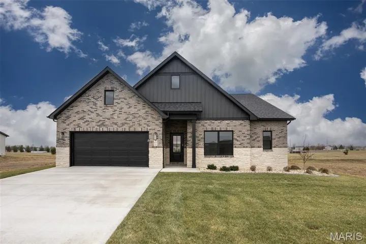 Modern farmhouse style home featuring board and batten siding, driveway, a front yard, brick siding, and roof with shingles
