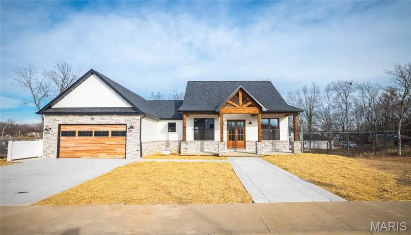 Modern farmhouse style home with covered porch, stone siding, concrete driveway, an attached garage, and a shingled roof