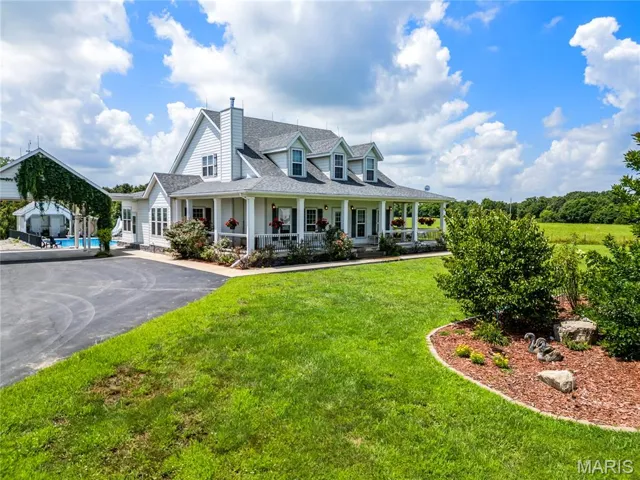 View of front facade with a porch, a shingled roof, a front lawn, a chimney, and an outdoor pool