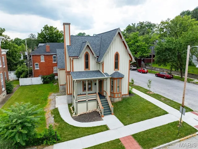 View of front of property with a shingled roof, a porch, board and batten siding, stairway, and a chimney