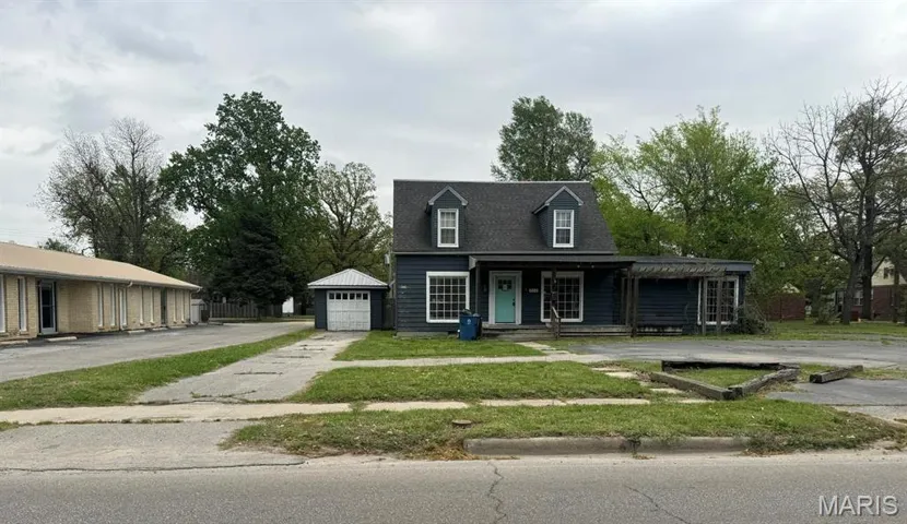 View of front of house featuring asphalt driveway, a porch, a garage, an outdoor structure, and a front yard