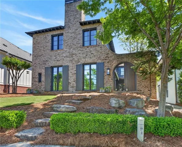 Brick exterior with chimney, arched entry, decorative window shutters, and stone pathway