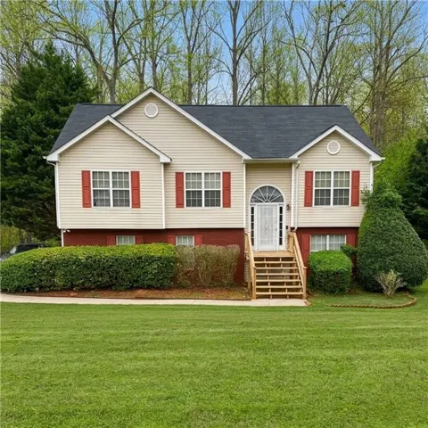 Raised ranch with a front yard and a shingled roof
