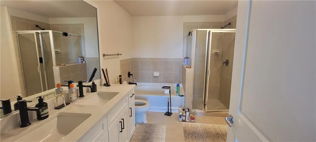 Full bath featuring a stall shower, a garden tub, a sink, and tile patterned flooring