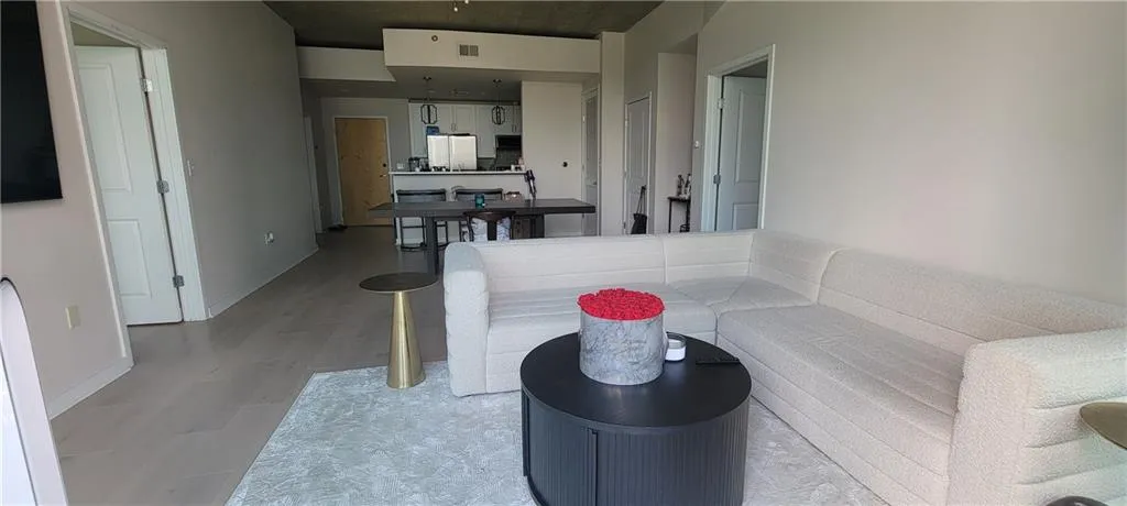 Living area with light wood finished floors, visible vents, and baseboards