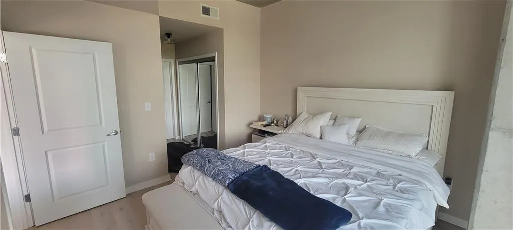 Bedroom with visible vents, baseboards, a closet, and wood finished floors