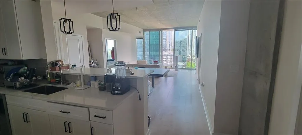 Kitchen with light wood-style flooring, a sink, light countertops, and expansive windows