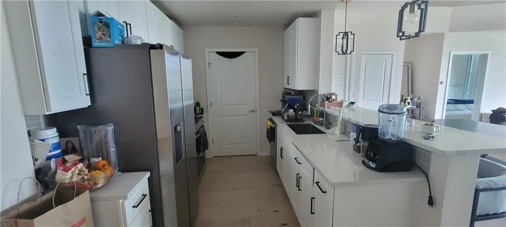 Kitchen with a peninsula, white cabinetry, light countertops, a sink, and a breakfast bar area