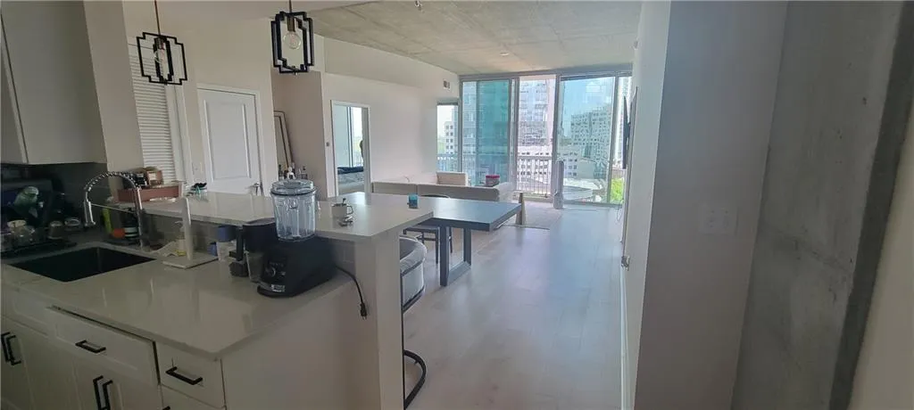 Kitchen featuring light wood-style flooring, white cabinets, a wall of windows, a sink, and light countertops