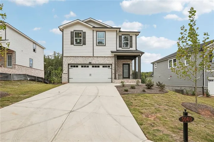 View of front of house featuring brick siding, a front lawn, driveway, and an attached garage