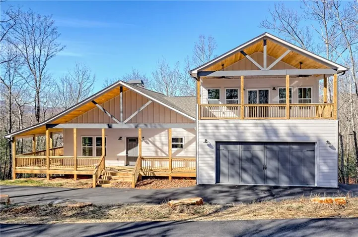 View of front of home featuring board and batten siding, a porch, driveway, an attached garage, and a ceiling fan