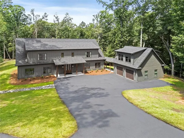 Contemporary home with vertical wood siding and a covered front porch featuring rustic columns