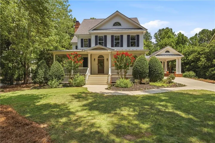Traditional-style residence featuring a white facade, dark shutters, and a covered front porch with white railings