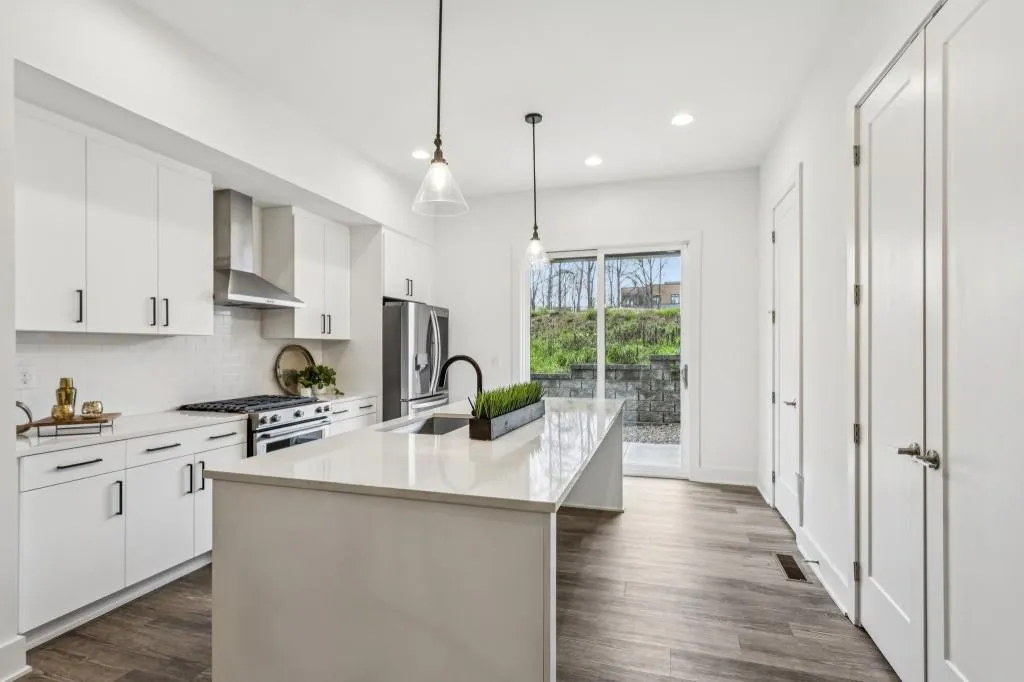 The beautifully appointed Kitchen features Quartz Countertops, crisp White Cabinetry, a classic Subway Tile Backsplash, Stainless Steel Appliances, and an oversized Kitchen Island   perfect for gathering with friends, casual meals, or morning coffee.