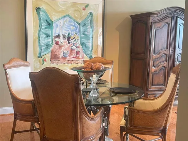Elegant dining room featuring a round glass-top table, leather upholstered chairs with wood frames, and hardwood flooring