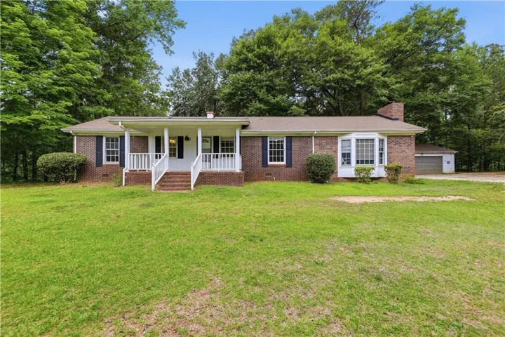 Brick exterior with a covered front porch featuring white railings and steps