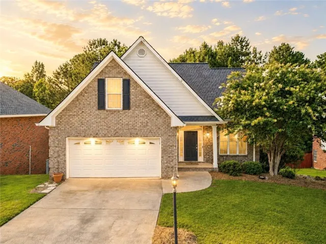 Charming brick and stone exterior with a two-car garage, gabled roofline, and covered entry