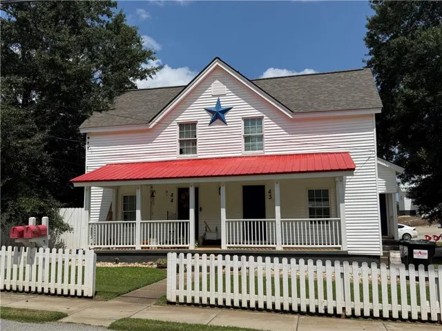 White siding exterior with a red metal roof porch