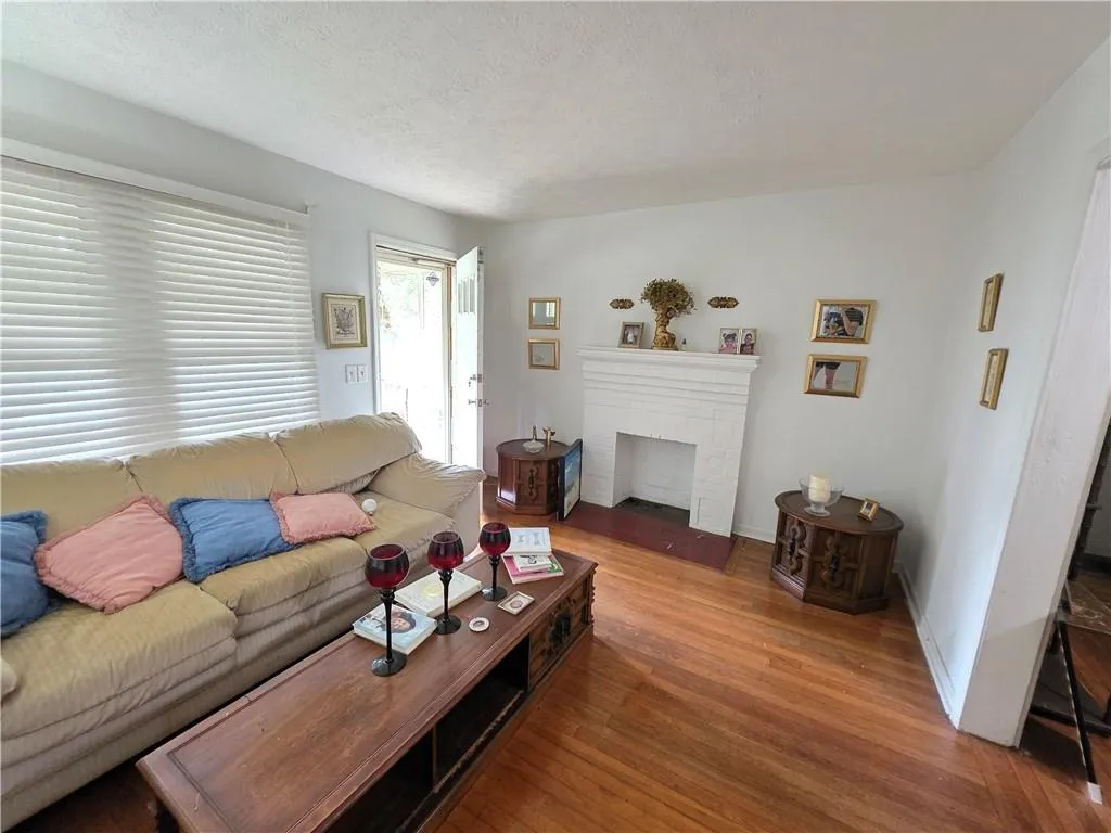 Living area with wood finished floors, a brick fireplace, and a textured ceiling
