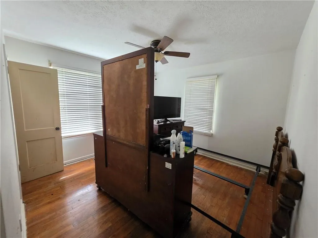 Office area featuring a ceiling fan, hardwood / wood-style flooring, and a textured ceiling