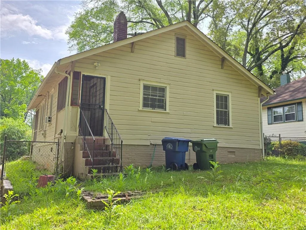 Back of house with entry steps, a chimney, and crawl space
