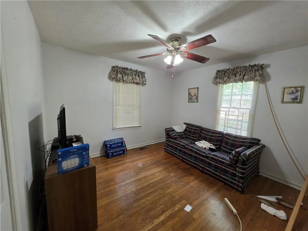 Living area featuring hardwood / wood-style flooring, ceiling fan, and a textured ceiling