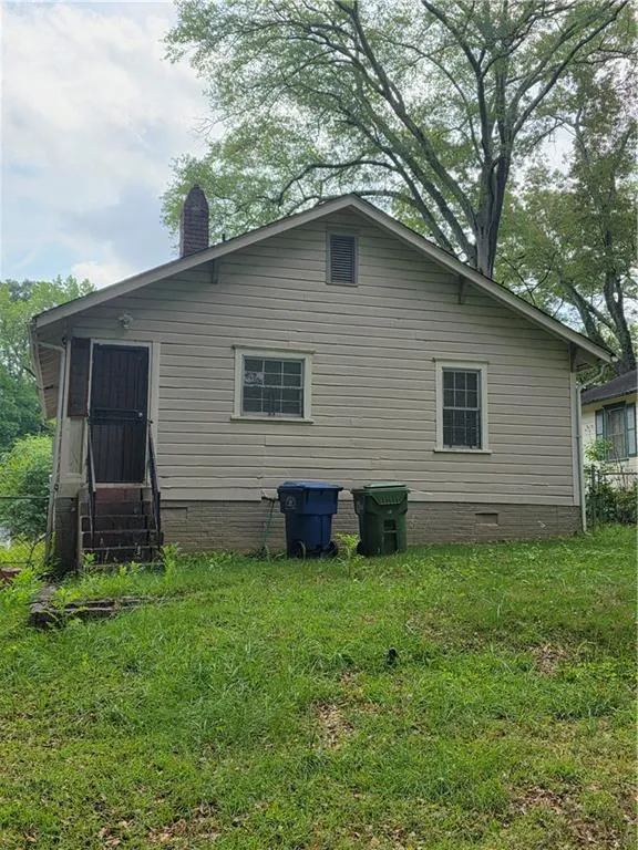 Back of house with entry steps, crawl space, a chimney, and a lawn