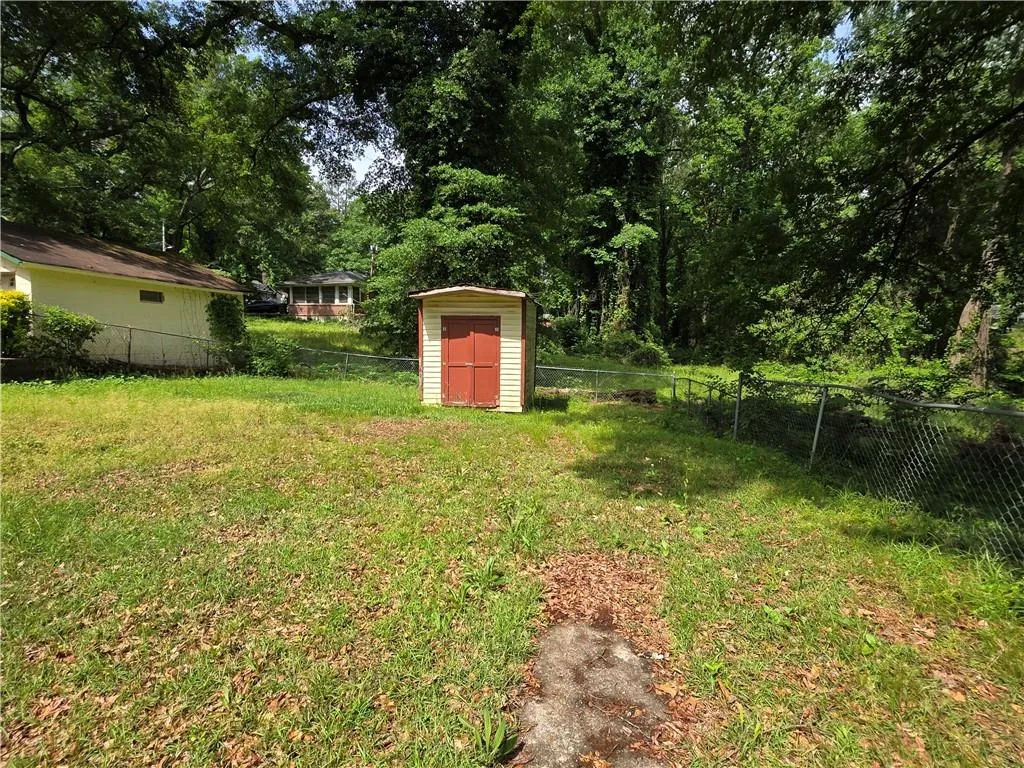 Fenced backyard featuring a shed