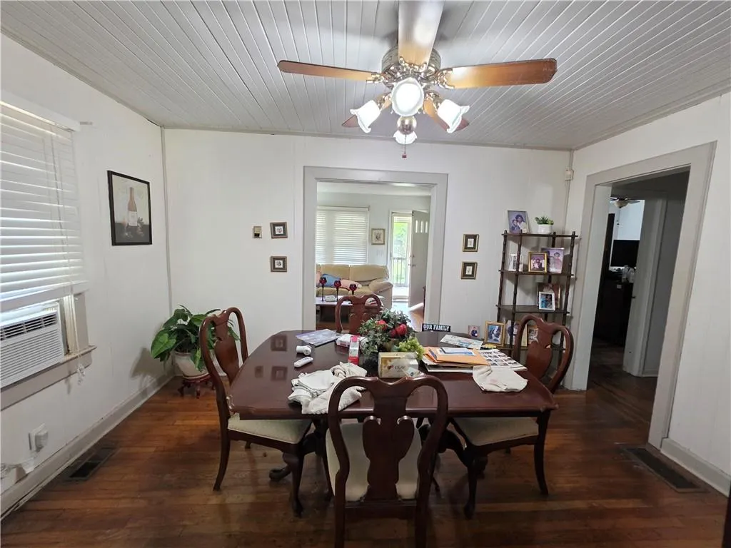 Dining space featuring a ceiling fan, dark wood-style flooring, cooling unit, and wooden ceiling