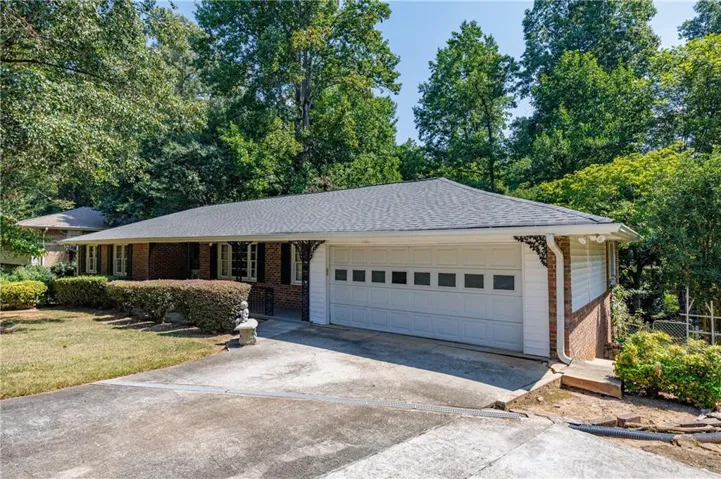 Brick exterior with dark shutters, attached garage, and a driveway