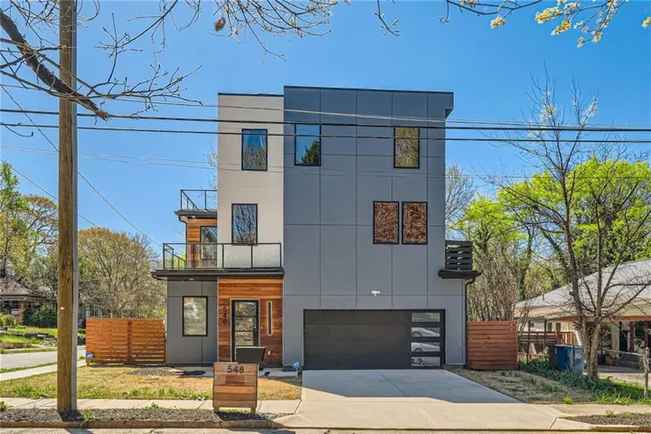 Contemporary three-story residence featuring a flat roofline and a combination of light and dark gray siding