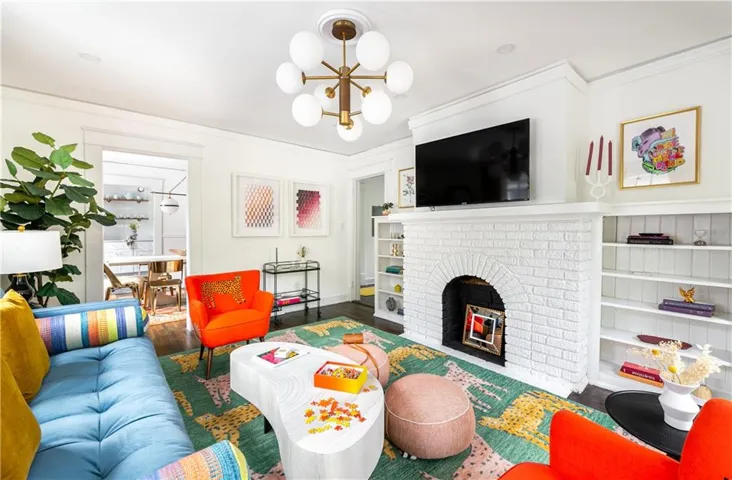 Living room with wood finished floors, crown molding, and a chandelier